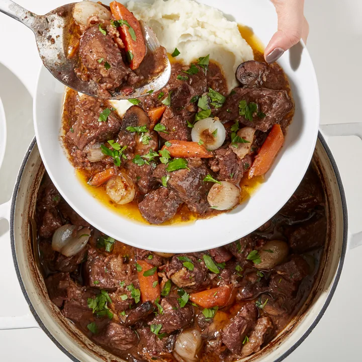 Beef bourguignon in pot spooned into dish